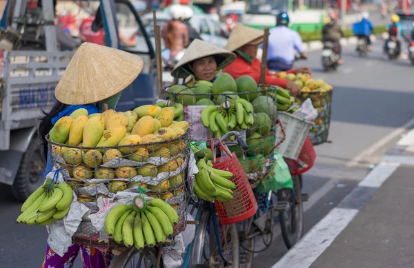 Typical street fruit vendor with palm-leaf conical hat moving at the street in road.