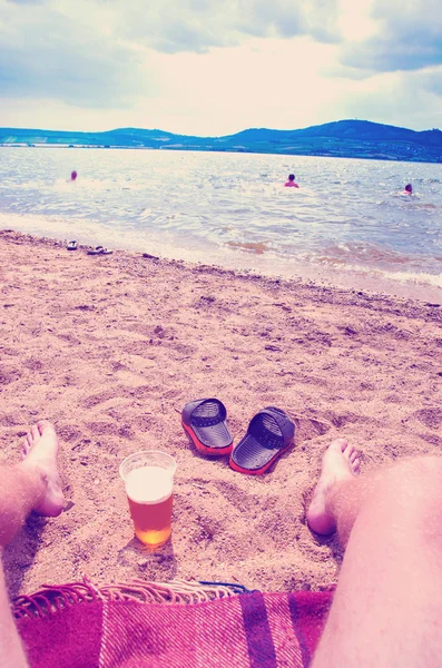 Wet boy\'s feet on the beach and sand with cup of beer with instagram effect retro vintage filter