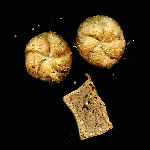 Bread roll and bread with seeds on a black background