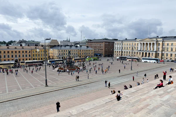 Many tourists and tour buses around the monument to Russian Emperor Alexander II on the Senate Square in Helsinki
