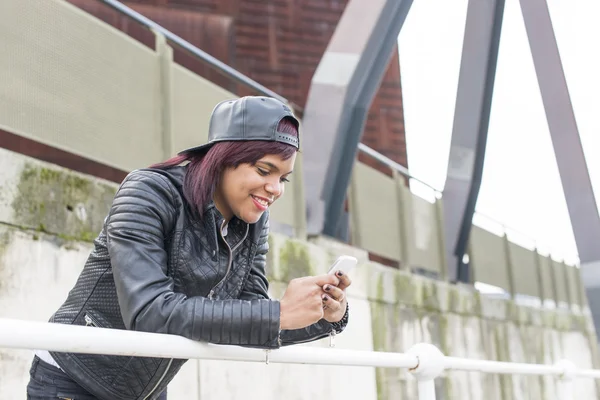 Smiling woman looking message on smart phone in the street, urban lifestyle concept.
