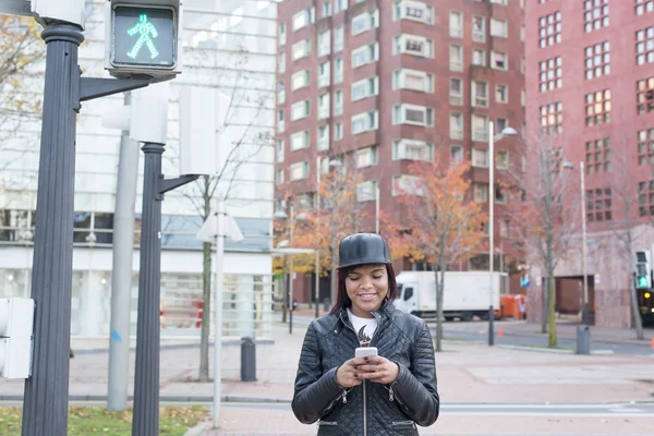 Smiling woman looking message on smart phone in the street, urban lifestyle concept.