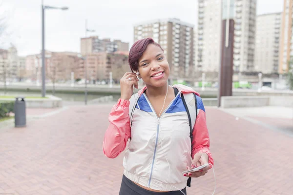 Smiling sport woman with headphones and smart phone.