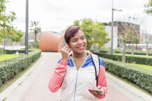 Smiling sport woman with headphones and smart phone.