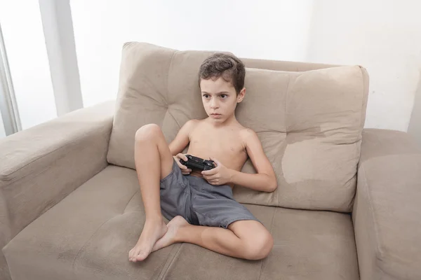 Boy in a summer sunny day playing video game at home