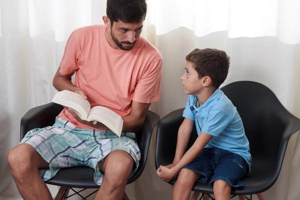 Father reading story book to the child in the living room