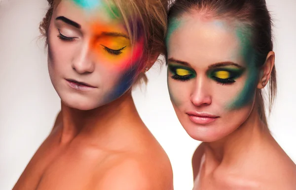 Cosmic beauty. Portrait of two beautiful women wearing artistic makeup posing with feathers white background