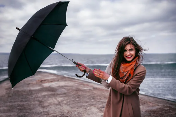 Redhead girl with umbrella by the sea