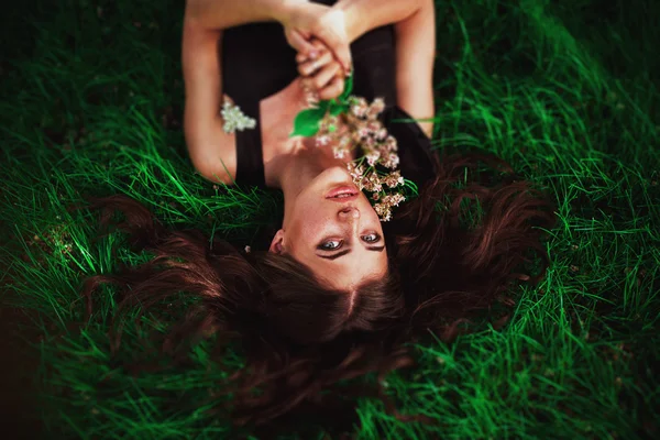 Close up portrait of young beautiful girl woman with red brown hair lying on grass with white small flowers around her head .View from above top overhead. Concept of spring summer youth happiness