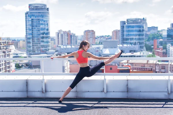 Beautiful woman doing a yoga exercise on he rooftop of a skyscraper