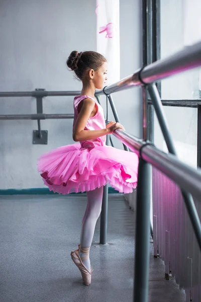 Beautiful little ballerina in pink dress in dance class