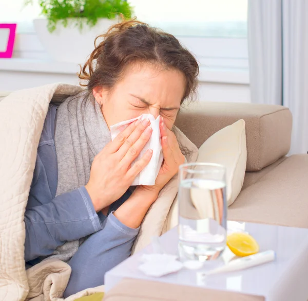 Sick woman sneezing into tissue.
