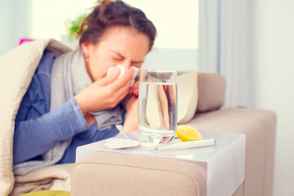 Sick woman sneezing into tissue.