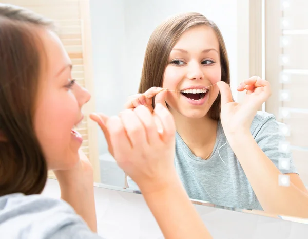 Teenage girl flossing her teeth