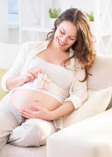 Pregnant  woman holding baby shoes
