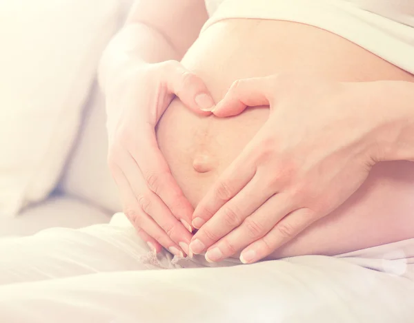 Pregnant woman holding hands on belly