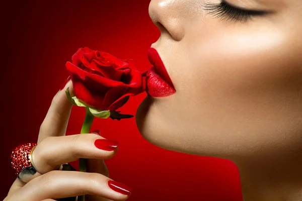 Beautiful  woman kissing red rose