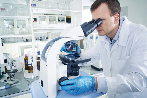 Scientist looking through microscope in laboratory