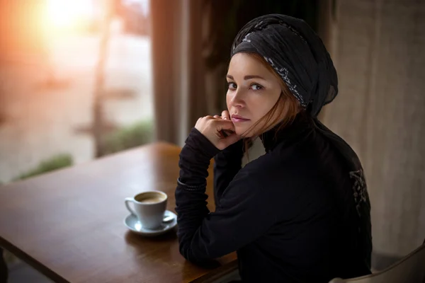 Beautiful Arab girl is drinking coffee in a cafe.