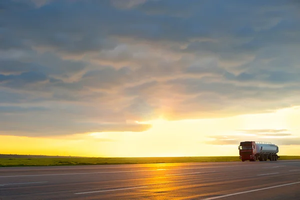 Truck moving on high-speed highway at sunset.