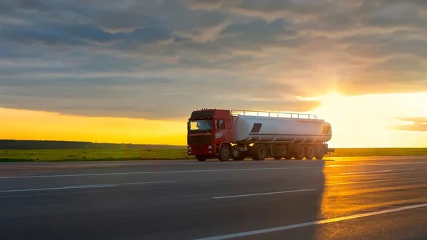 Truck moving on high-speed highway at sunset.