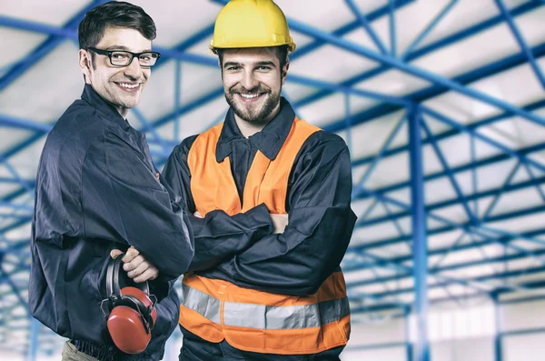 Smiling workers in protective uniforms in production hall