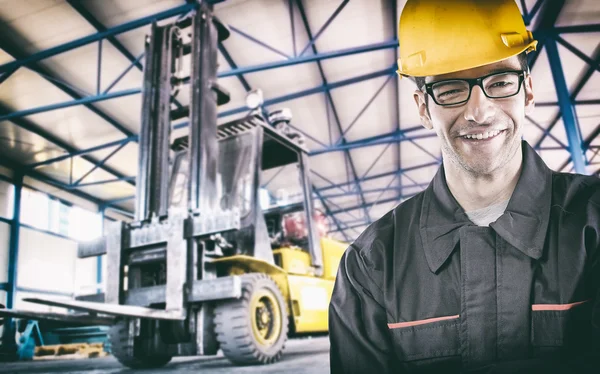 Smiling worker in protective uniform in front of forklift