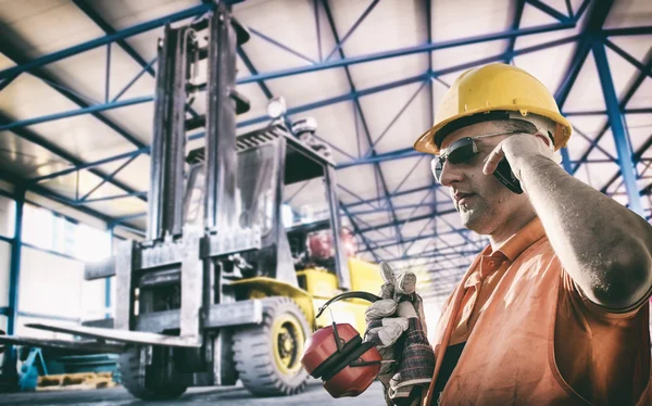 Worker in protective uniform in front of forklift