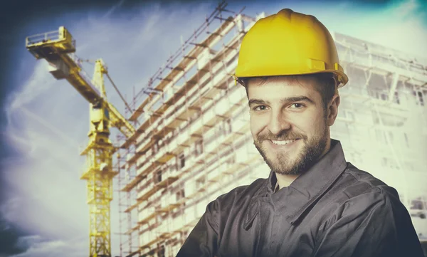 Smiling worker with protective uniform in front of construction