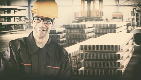Smiling worker with protective uniform in front of metal proflie