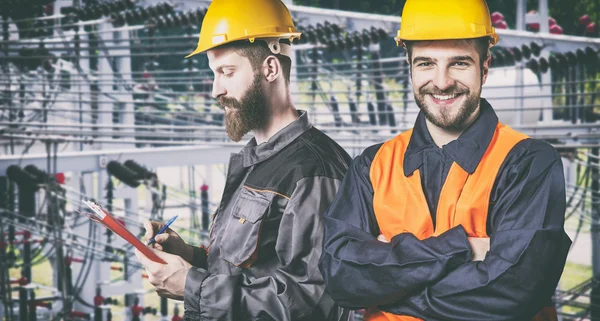 Smiling workers with protective uniforms in front of power plant