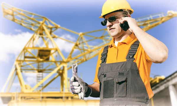 Worker in protective uniform and protective helmet in front of c