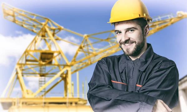 Smiling worker in protective uniform and protective helmet in fr