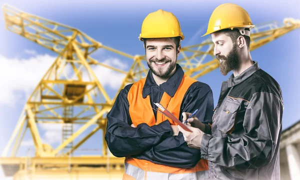 Smiling workers in protective uniforms in front of construction