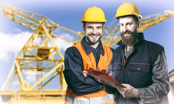 Smiling workers in protective uniforms in front of construction