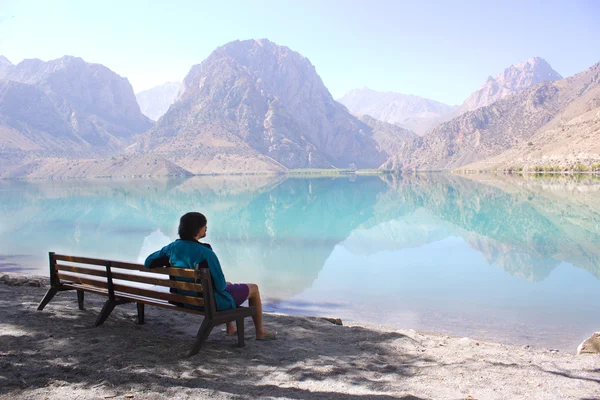 Young man sitting on bench near mountain lake Iskanderkul, centr