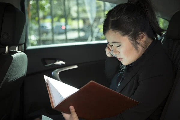 Chinese businesswoman working in back of limousine