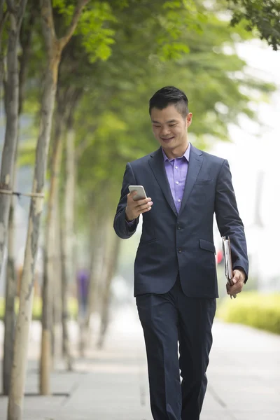 Chinese businessman walking and using Smartphone