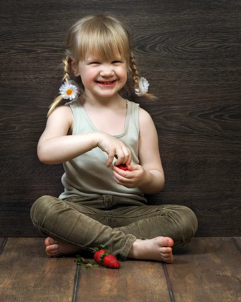 Funny and happy little girl eating a strawberry