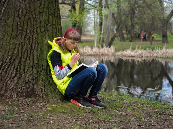 Teen girl in the park with a book