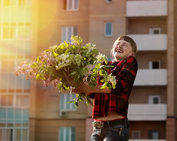 Happy girl with big bouquet of flowers laughing happily in the sun