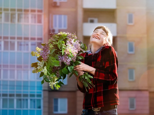 Happy girl with big bouquet of flowers laughing happily in the sun