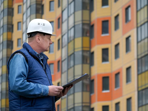 Engineer standing against the background of a new block of flats