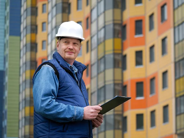 Engineer standing against the background of a new block of flats