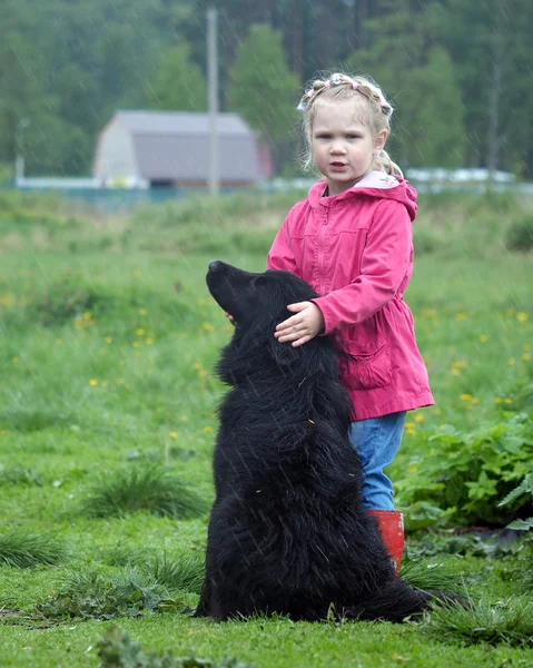 Little girl and big black dog in the rain