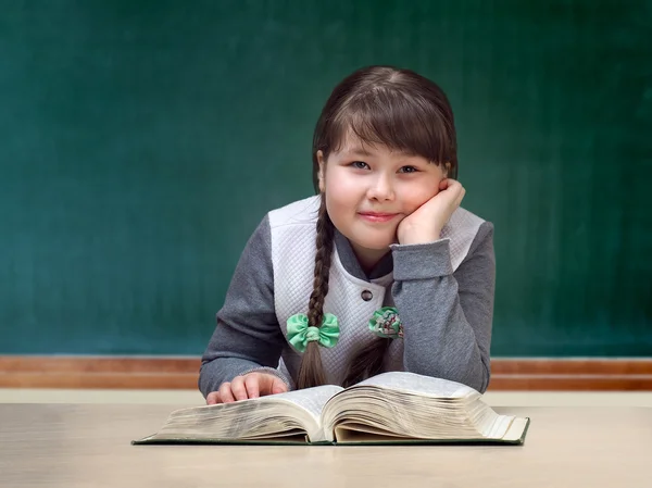 Girl in the classroom daydreaming, smiling. Great tutorial. Blackboard. Child obesity full. Portrait of a schoolgirl.