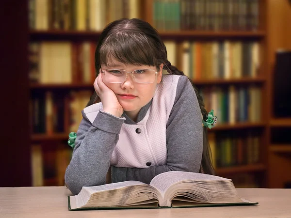 The girl in the library with a book and glasses. The concept of overweight teenage complexes, difficulties at school