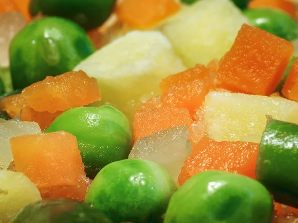Frozen vegetables, mixed vegetables. Peas, carrots, potatoes. Photographed close-up (macro). Vegetarian dishes