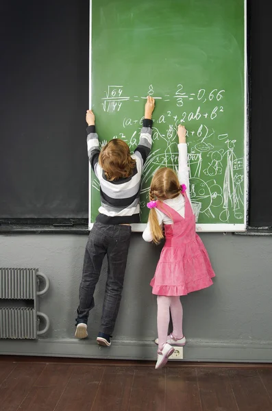 Children write formulas on the blackboard in the classroom. School. High School, College