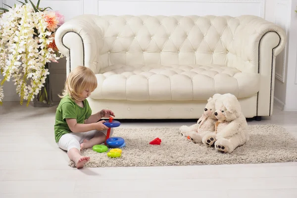 A child plays in a beautiful room with a bright toy pyramid.